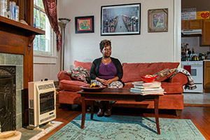 A photo of a woman, photographed as part of The Debt Project, sitting in her living room